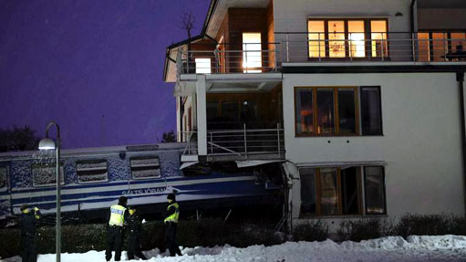Police officers stand around a local train that derailed and crashed into a residential building in Saltsjobaden outside Stockholm